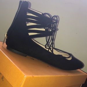 Black laced flats with a zipper in the back .